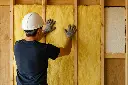 Drywall Insulation – Contractor Installing Fiberglass Batt in Wall Studs.webp